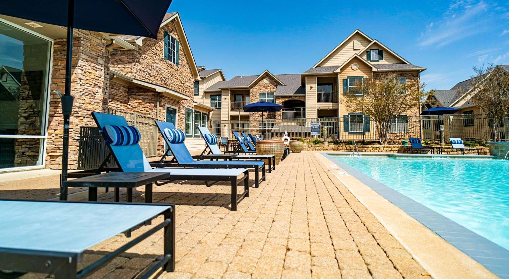 Resort-style swimming pool umbrella shaded lounge chairs next to pool